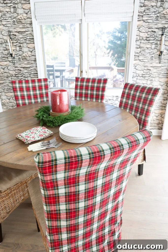 Looking down at a round dining table where all the chairs are covered in a classic red and white Christmas plaid fabric.