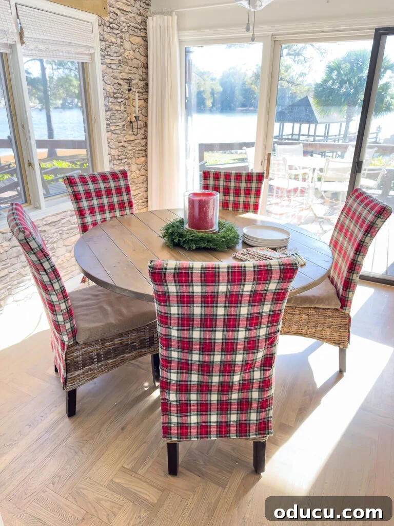 Round wood kitchen table with Christmas plaid fabric covered dining chairs around it.