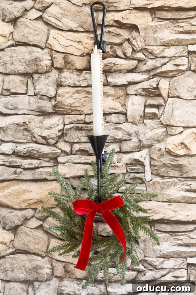 My Christmas Home: Timeless Memories, Not Trends 13 wall candle sconce on stone wall decorated for Christmas with greenery wreath and red velvet ribbon.