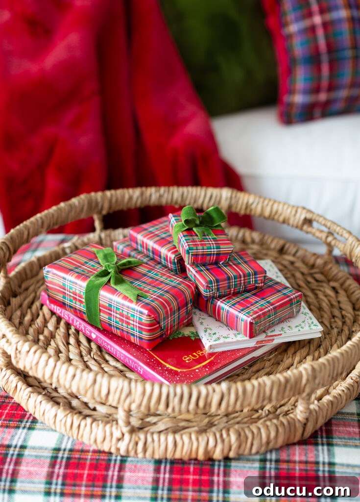 My Christmas Home: Timeless Memories, Not Trends 7 a stack of small plaid gift wrapped boxes on a woven round tray on a plaid covered ottoman.