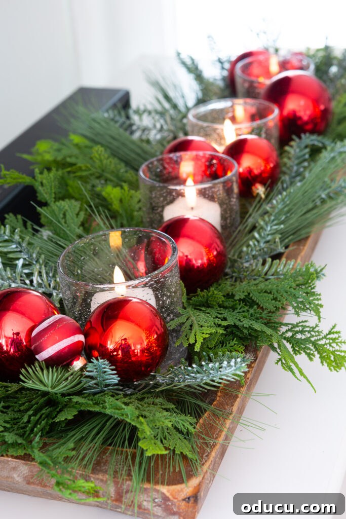 My Christmas Home: Timeless Memories, Not Trends 9 a dough bowl decorated for Christmas with greenery, glass candles votives and red ball ornaments.