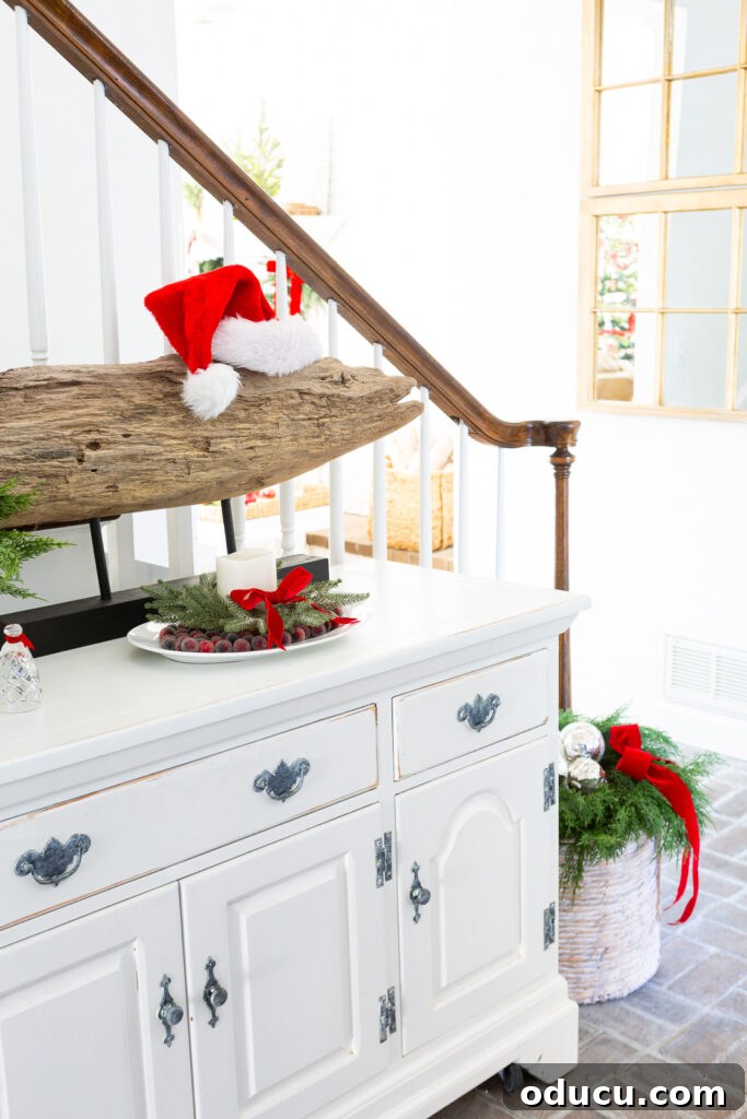 The Wreath Revelation You Need This Christmas 10 The inviting foyer showcases delightful Christmas decor, including a sideboard arrangement and a festive basket display.