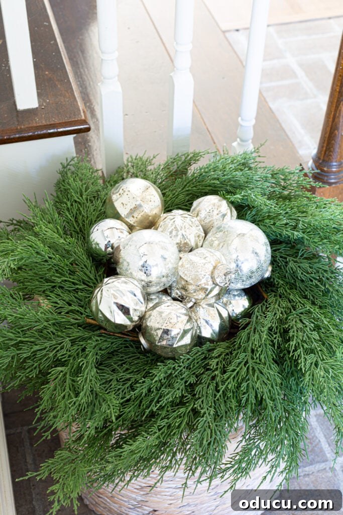 The Wreath Revelation You Need This Christmas 6 A close-up view of silver Christmas ornaments meticulously placed within a lush greenery wreath, resting on a floor basket.