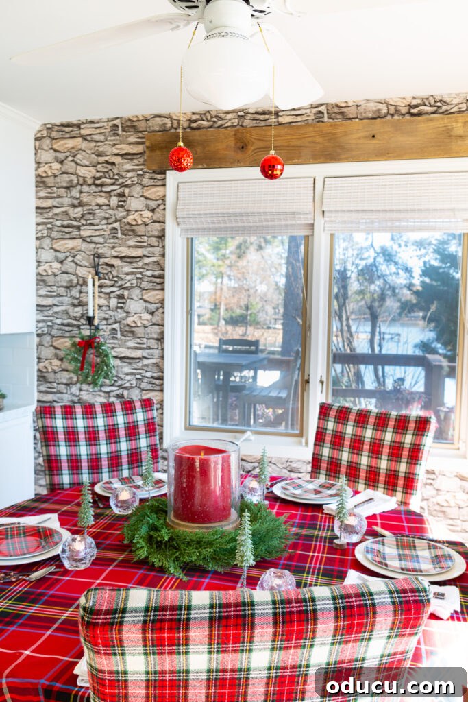 Red plaid decorated kitchen for Christmas with 2 red ornaments hanging at the end of the pull chains on the light fixture above the dining table.