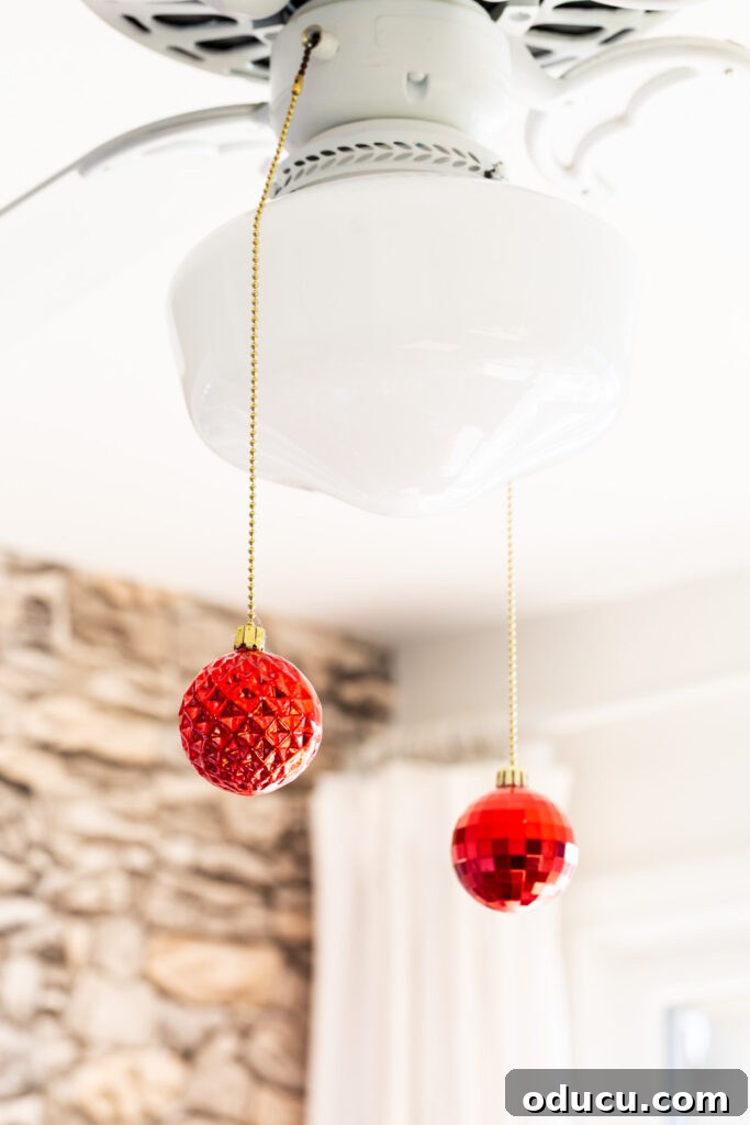 two pull chains on a ceiling fan with Christmas ornaments added.