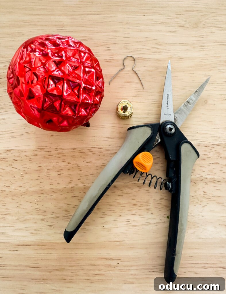 a red Christmas ornament with top taken out and cutting snips