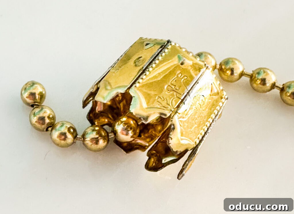 close up of how to thread ceiling fan chain through top of ornament top.