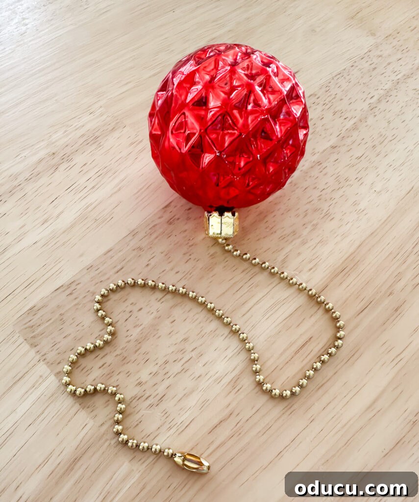 a close up of a Christmas ornament added to a ceiling fan pull chain to create festive holiday touch.