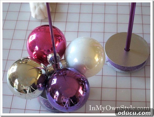 First Layer of Ornaments The first layer of four large ball ornaments threaded onto a knitting needle, forming the stable base of the tabletop Christmas tree.