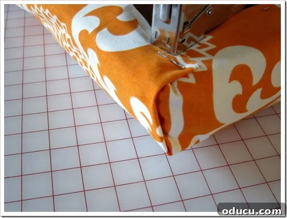 Step-by-step imagery for creating neat corners on a no-sew cushion cover. Detailed view of folding and stapling fabric for a no-sew cushion corner.
