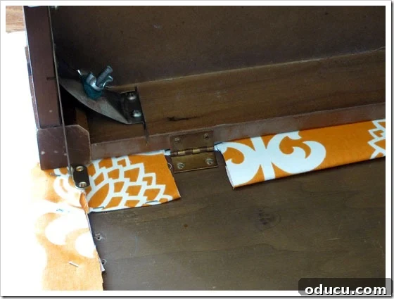 Final step: Reattaching the upholstered bench lid. Reattaching the newly upholstered lid to the piano bench with hinges.
