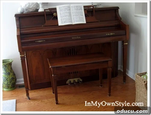 Before shot of a piano bench, showing its original dark brown appearance. The dark brown piano bench before its no-sew cushion makeover.