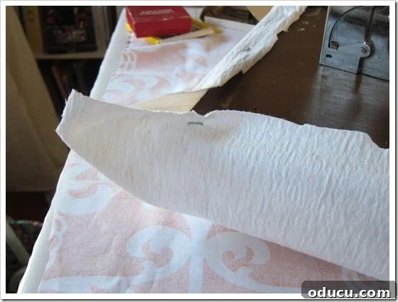 Detailing the process of securing the first layer of fabric for a no-sew cushion. Stapling the initial white lining fabric onto the bench cushion.