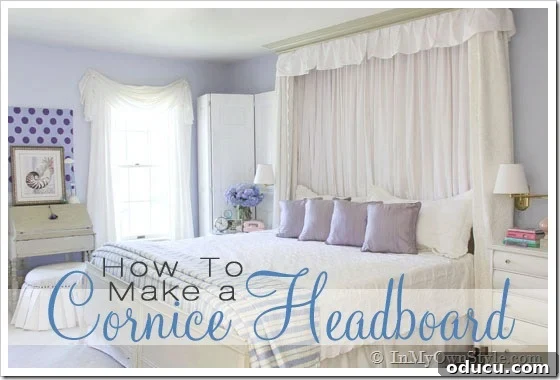 A custom cornice headboard mounted above a bed, featuring elegant crown molding and soft fabric pleats, enhancing a white and blue bedroom's aesthetic.