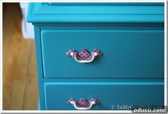 From Worn Out to Wonderful Painting an Old Chest of Drawers 2 Close-up of purple napkin-covered drawer pulls against a turquoise painted chest of drawers, highlighting the unique hardware makeover.