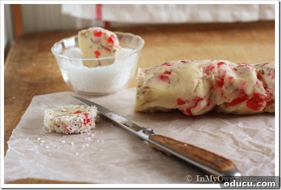 Christmas Cookie Baking Ideas using pecan and candied cherries Chilled dough logs being cut and then dipped into sanding sugar for a festive coating.