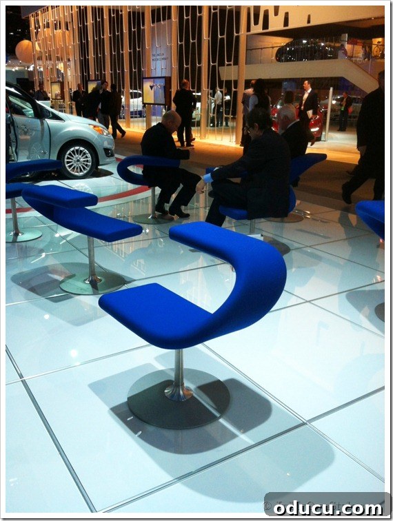 A stylish, modern lounge chair at the auto show, designed for comfort and connectivity.