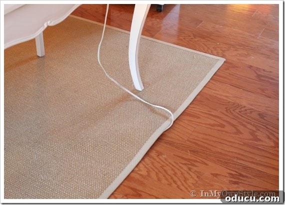 Clutter-Free Desk: DIY Cable Management 5 An electric cord safely hidden under a rug with a cord protector