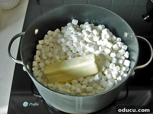 Popcorn-Cake-Cooking on stove Marshmallows, margarine, and oil melting together in a pot on the stovetop, forming a smooth, sticky mixture.