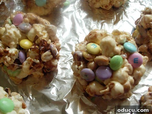 Popcorn-cake-on-foil Popcorn mix formed into neat balls, cooling on a sheet of foil, ready for individual serving or further decoration.