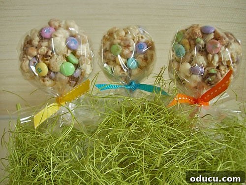 Popcorn-Cake-Lollipop recipe and directions Popcorn cake recipe shaped into lollipops with sticks, tied with ribbon, and displayed on Easter grass for a festive look.