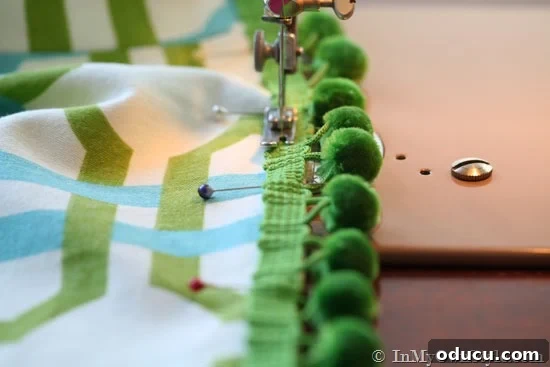 How-to-sew-trim-on-cushion-covers Detailed shot of pom-pom trim being pinned onto the hem of a cushion cover, illustrating proper technique for attaching decorative elements.