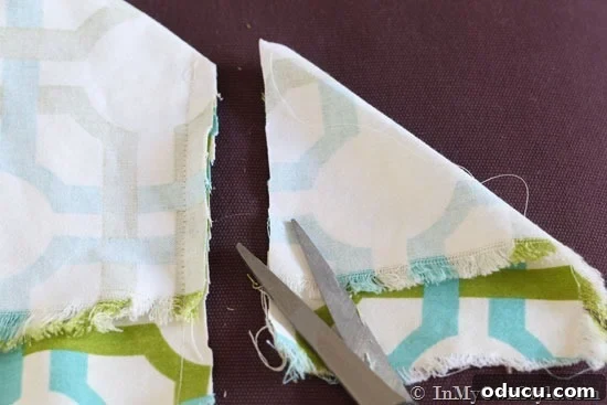 Cutting-corners-on-cushion-covers Close-up of fabric corners being pinned and cut for an ottoman cushion cover, demonstrating precision in DIY sewing.