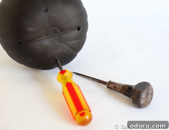 Close-up of a foam pumpkin being painted black with chalkboard spray paint.