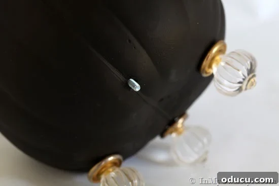 Demonstration of attaching a cabinet knob as a foot to a foam pumpkin, showing the screw coming through.