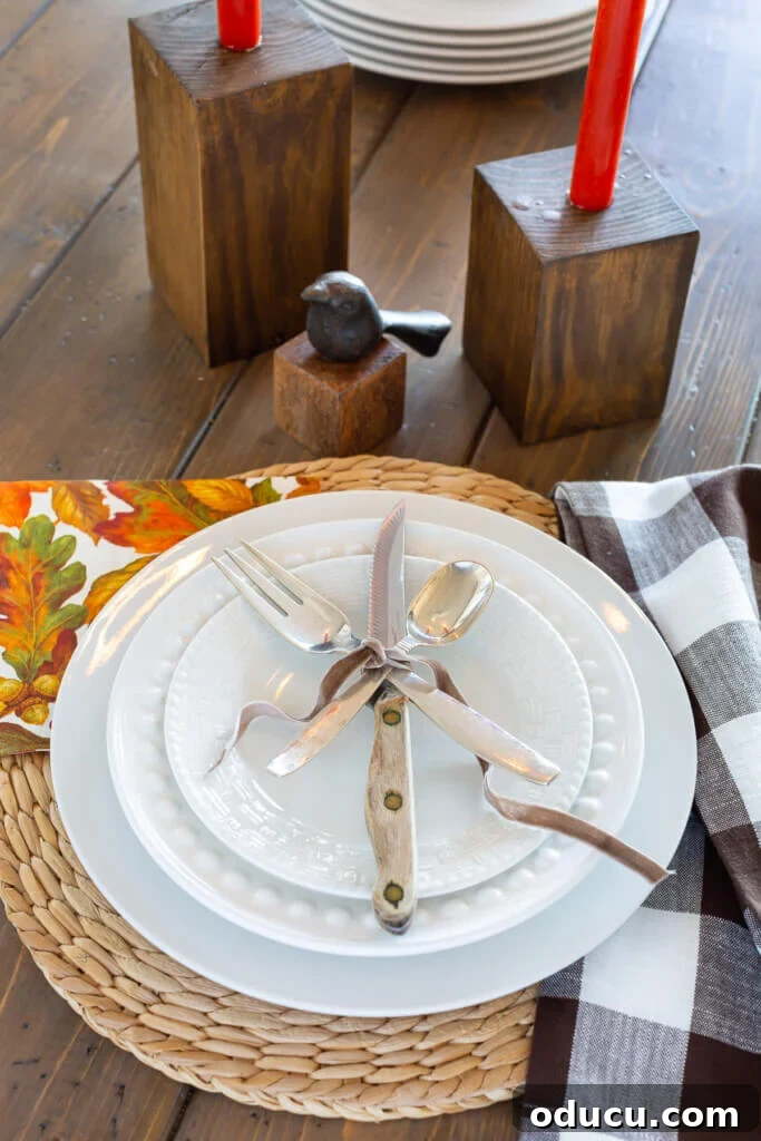 Table place setting of a white dinner plate layered with a fork, knife, and spoon tied with brown ribbon, a simple solution for utensil placement.