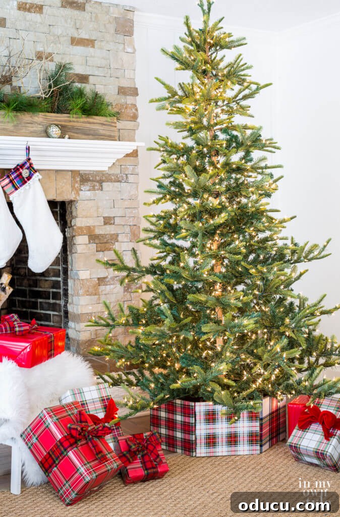 Upcycled Photo Frame Christmas Tree Skirt 2 Living room with a beautifully decorated Christmas tree featuring a plaid fabric-wrapped photo frame tree collar around its base, creating a cozy and inviting atmosphere.