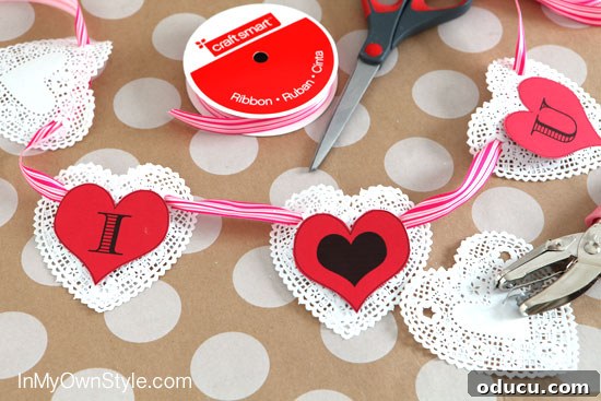 Heartfelt Initial Crafts: Free Valentine Printables 5 Easy-to-make DIY Valentine banner featuring paper doilies and initial heart cutouts, perfect for quick and charming decoration.