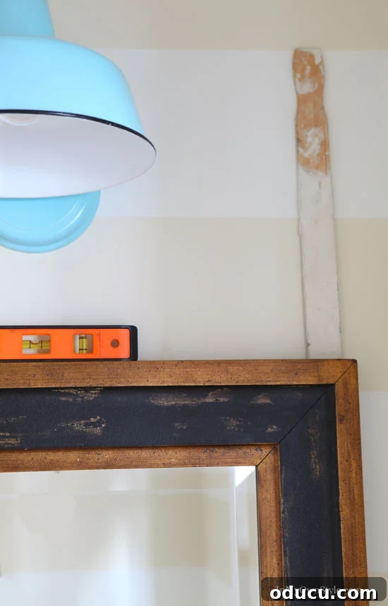 Instant Wall Decor: Hang Art & Mirrors Like a Pro 5 Easy way to hang a mirror, showing the mirror on the wall with the gadget still attached to its top corner.