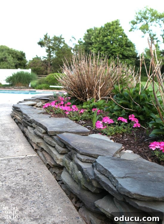 Completed garden landscape with a fieldstone wall and vibrant plants