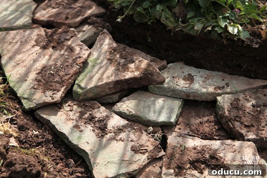 Adding another layer of fieldstones to the garden wall