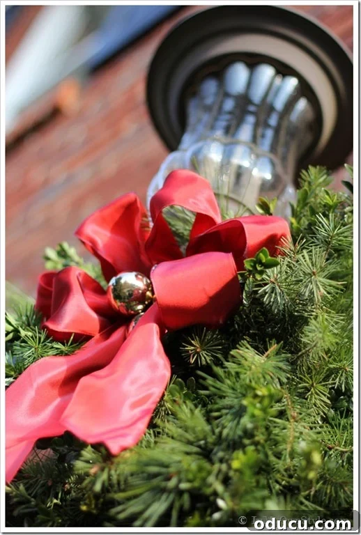 Ribbon Flair for Instant Home Style 23 Outdoor house lights decorated for Christmas with red ribbon and pine greenery, creating a welcoming festive display.