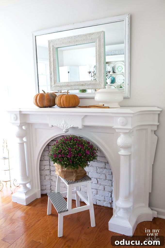 Effortless Autumn Pumpkin Decorating 19 A cozy fall home tour scene showing a simple yet effective fireplace mantel decor with a pumpkin alongside a pot of mums, ideal for a brick wall.