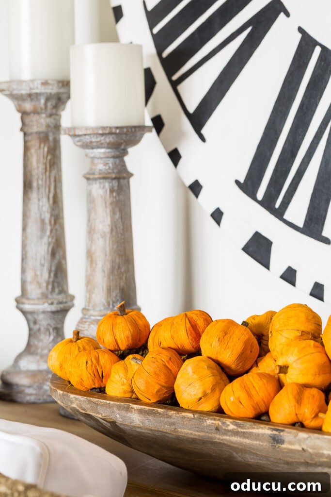 Effortless Autumn Pumpkin Decorating 9 A rustic long wooden dough bowl filled with an abundance of mini paper pumpkins, creating a charming and abundant fall centerpiece for a console table.