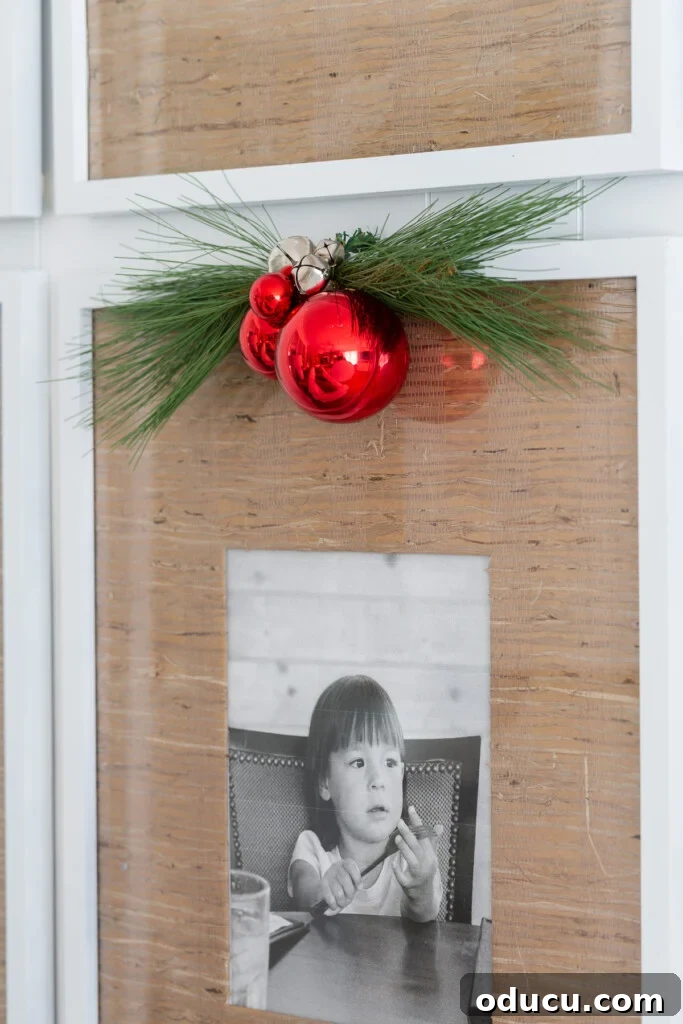 red ball ornaments and greenery hanging on a framed photo, adding a festive touch.