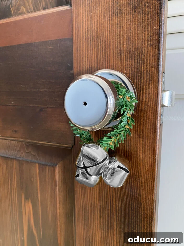 Christmas garland tie wrapped around a doorknob with jingle bells attached, creating a festive sound.