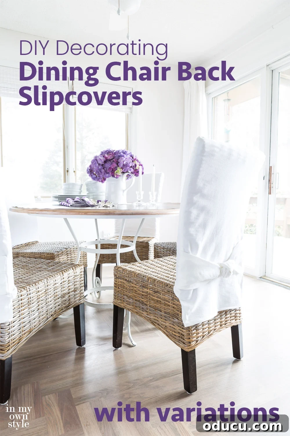 Transform Your Dining Chairs with Easy DIY Slipcovers 15 Casual dining area in a home with table and chairs. Chairs are wicker and have white chair back slipcovers on them. A white pitcher on the table has purple hydrangeas in it. A welcoming dining room, beautifully transformed with DIY chair back slipcovers, showcasing the blend of practicality and aesthetic appeal.