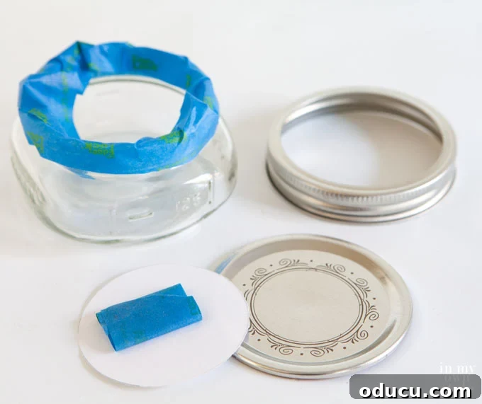 Detailed step-by-step image showing how to mask a Mason jar lid with a label before applying glitter for Christmas crafts.