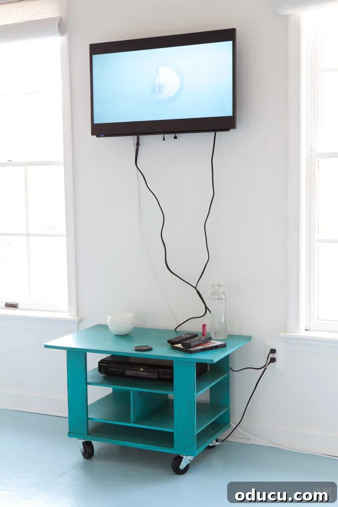 Flat screen TV mounted on a wall with visible cords hanging down.