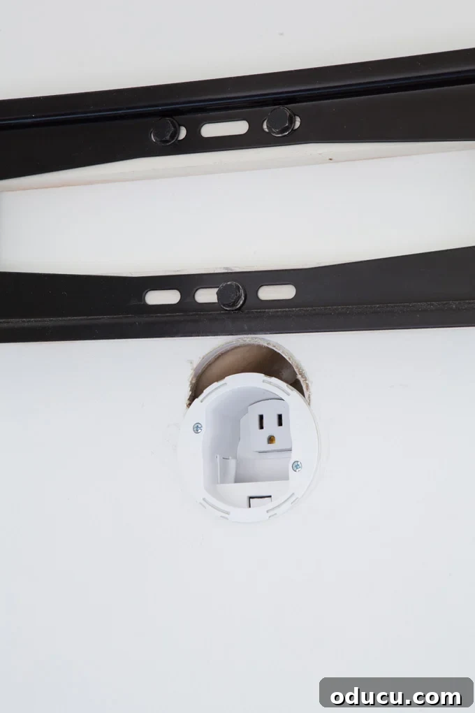 Wall Mounted TV bracket Close up of TV cord hiding kit and outlet on wall.