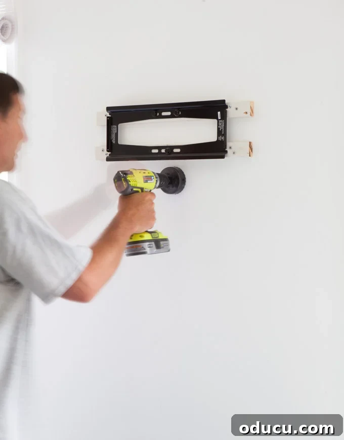 How to drill holes in the wall to hide wires on a wall mounted TV Man drilling hole in wall for TV cord kit to go into.