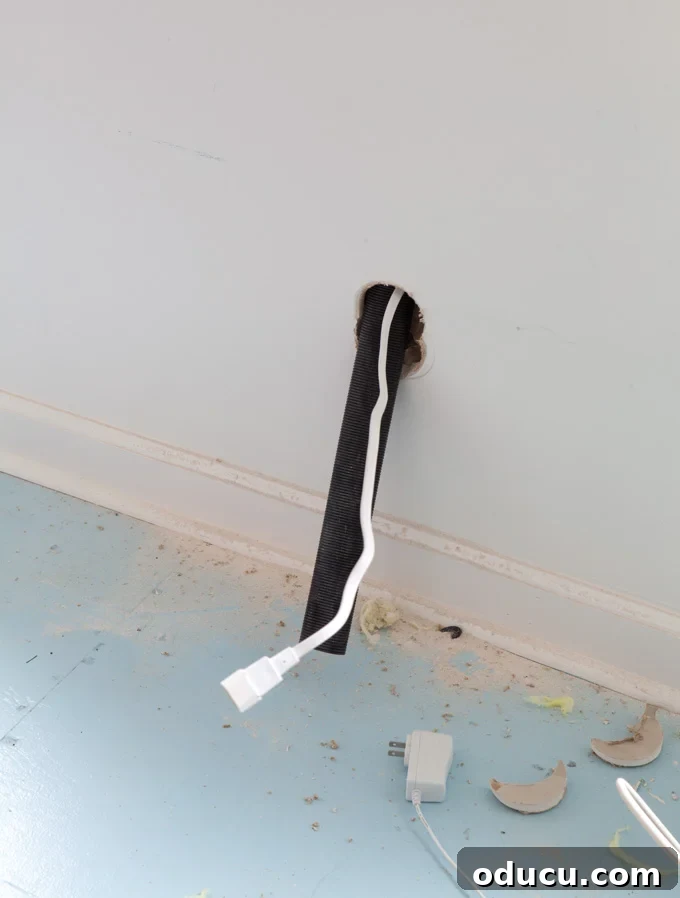 Steps needed to hide the cords on a wall mounted TV Cord and kit tube coming out of lower hole made in the wall.