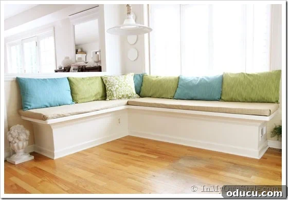 Craft Your Custom Kitchen Banquette 4 Custom built-in banquette in a kitchen, updated years later with new fabric covers and cushions, featuring a round table and colorful chairs.