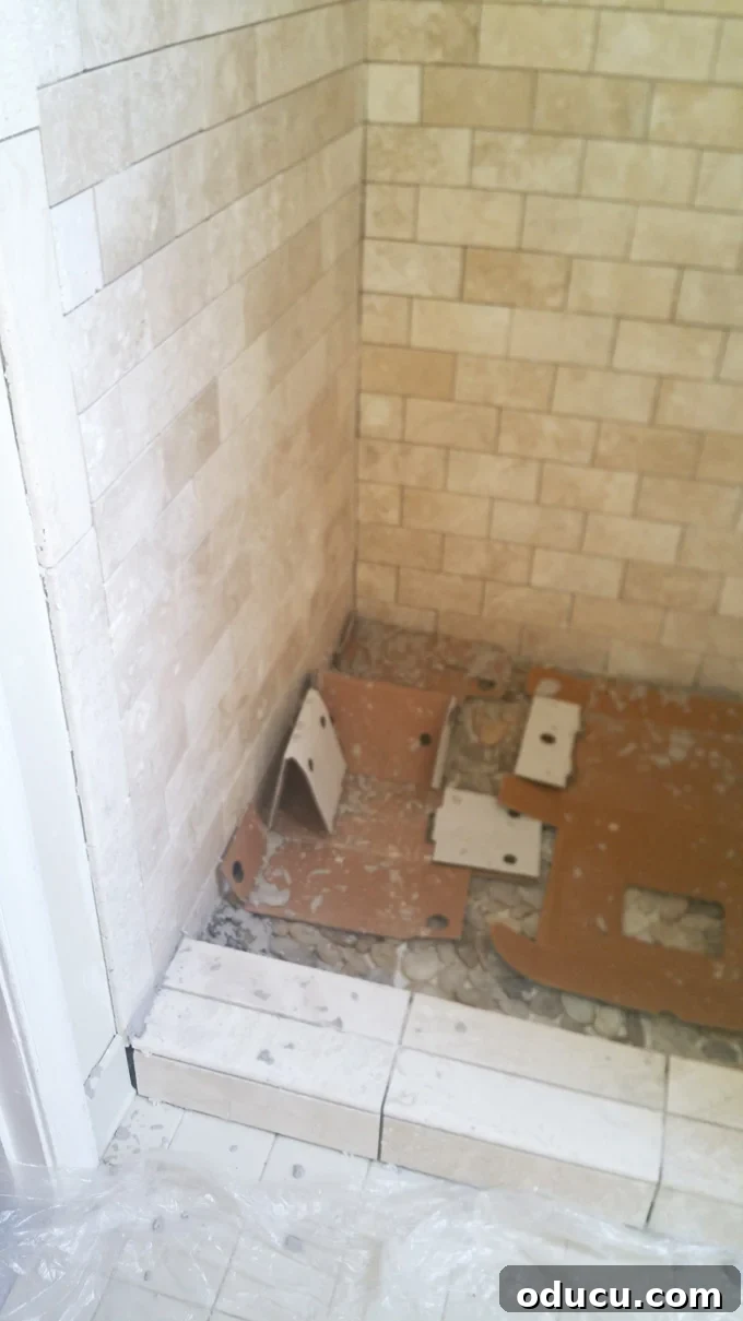 Luxury Master Shower Transformation 11 A contractor meticulously applying grout to the newly installed stone tiles in a shower, showcasing the final stages of the renovation.