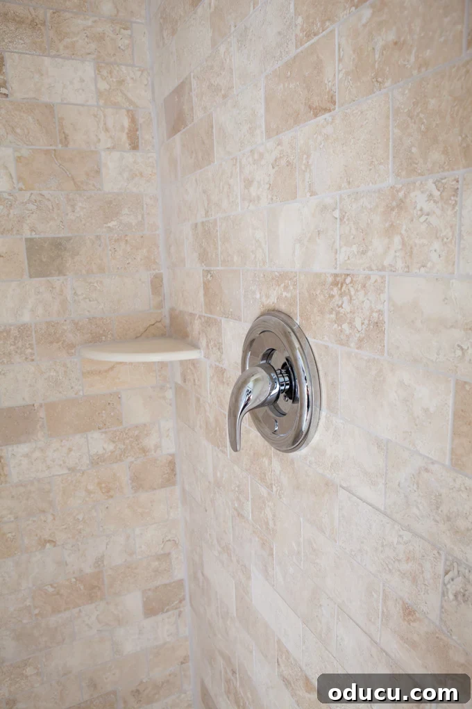 Luxury Master Shower Transformation 12 Shiny silver shower faucet handle beautifully contrasted against the texture of the new stone tiles in the master bathroom shower.