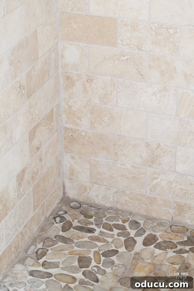 Luxury Master Shower Transformation 14 Tumbled stone tiles used in the shower, showcasing both wall and floor applications with complementary textures and tones.